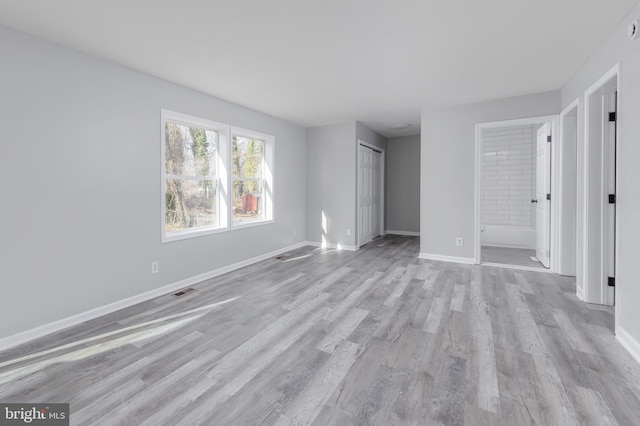 unfurnished bedroom with light wood-type flooring, ensuite bath, and a closet