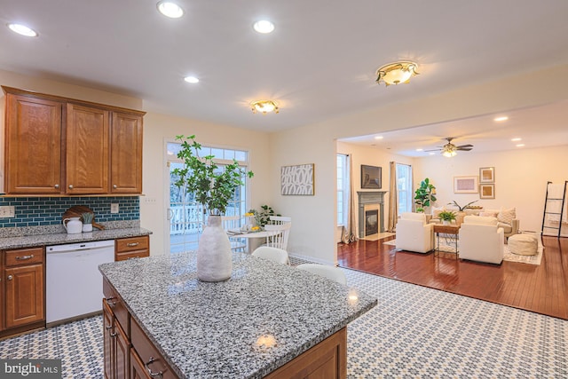 kitchen with light stone countertops, ceiling fan, dishwasher, and a center island