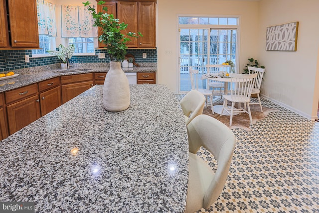 kitchen with tasteful backsplash, a healthy amount of sunlight, light stone countertops, and sink