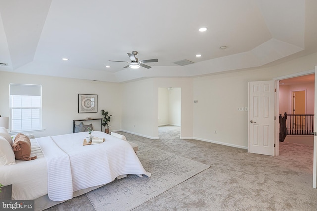 carpeted bedroom with ceiling fan and a raised ceiling