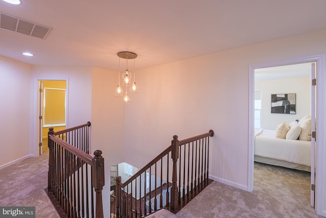 hallway featuring carpet flooring and a notable chandelier