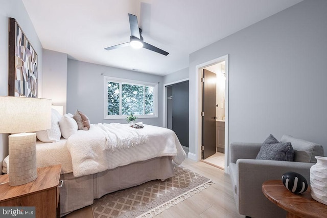 bedroom with ensuite bathroom, light hardwood / wood-style flooring, and ceiling fan