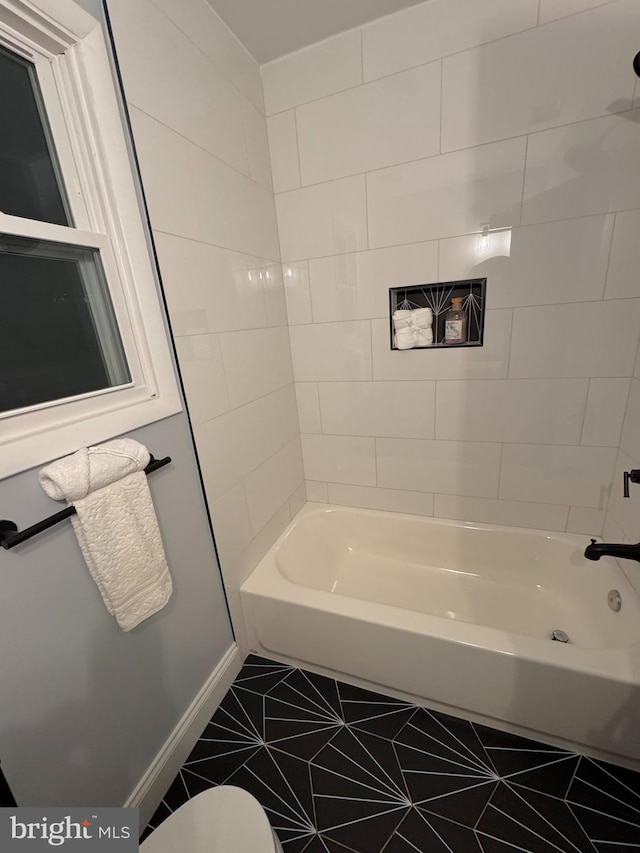 bathroom with tile patterned floors, toilet, and tiled shower / bath