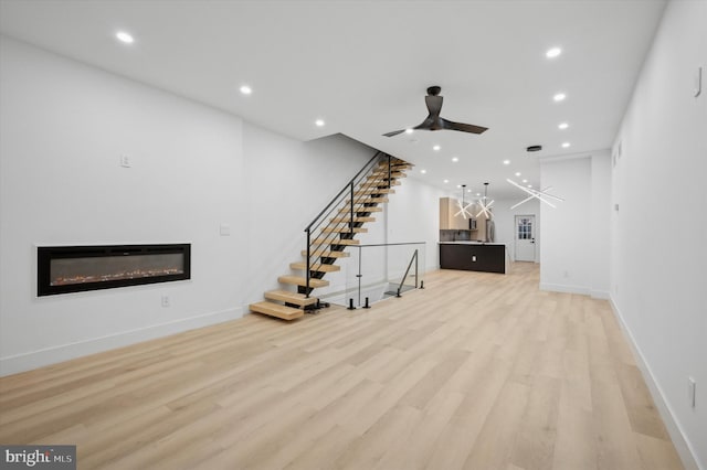 unfurnished living room featuring ceiling fan and light wood-type flooring