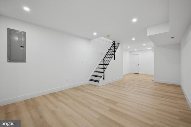 basement with electric panel and light hardwood / wood-style flooring