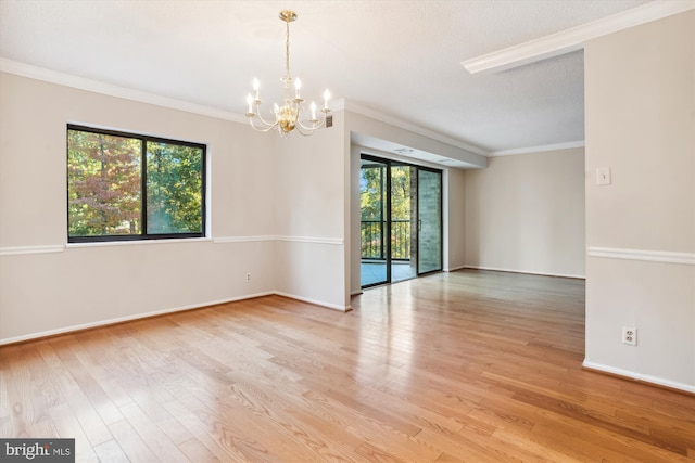 spare room with a textured ceiling, light hardwood / wood-style flooring, crown molding, and an inviting chandelier