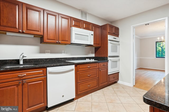 kitchen featuring dark stone countertops, sink, a chandelier, and white appliances