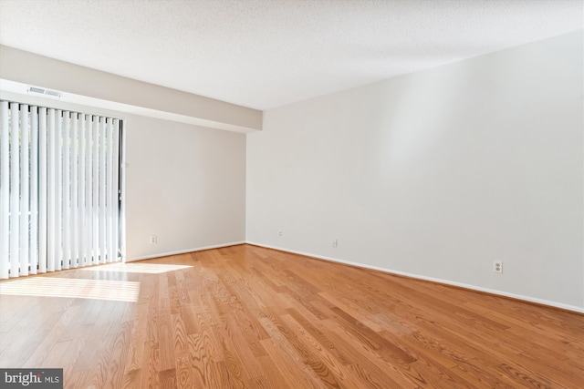 spare room with a textured ceiling and light hardwood / wood-style floors