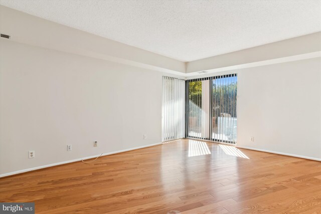 empty room with a textured ceiling and light wood-type flooring