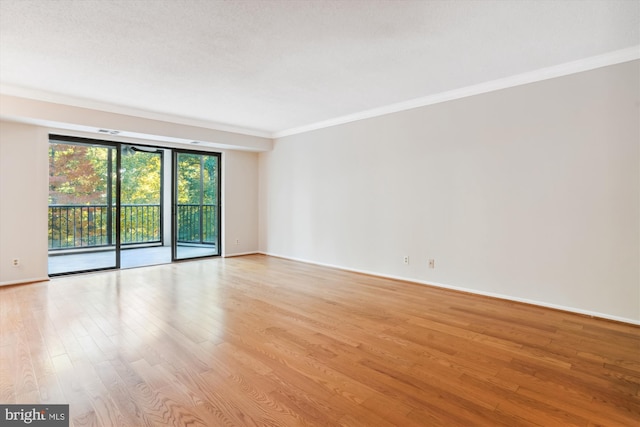 spare room featuring a textured ceiling, light wood-type flooring, and crown molding