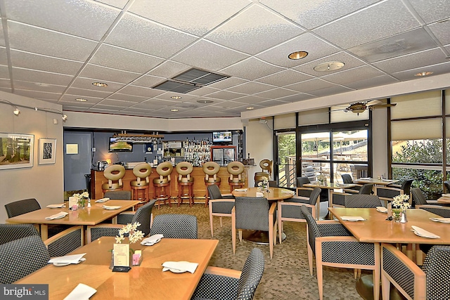 carpeted dining area featuring a paneled ceiling and ceiling fan