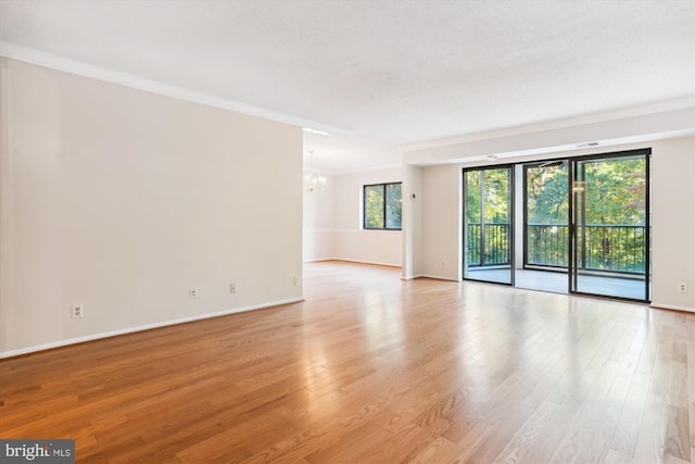 spare room with ornamental molding, light hardwood / wood-style floors, and an inviting chandelier