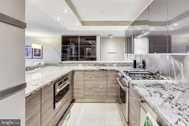 kitchen with light stone counters, light tile patterned floors, kitchen peninsula, and appliances with stainless steel finishes