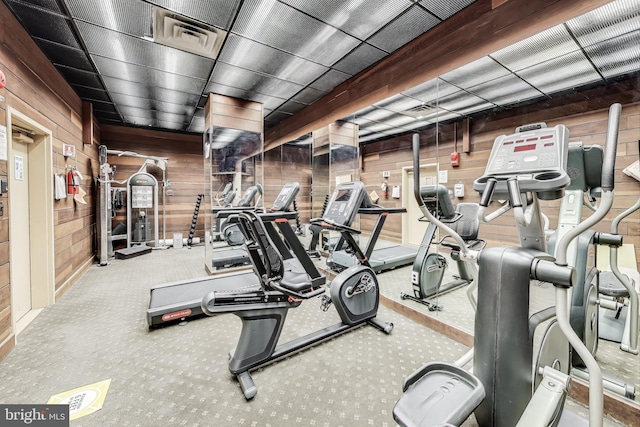 workout area featuring carpet flooring and wooden walls