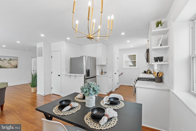 dining area with light hardwood / wood-style floors and an inviting chandelier