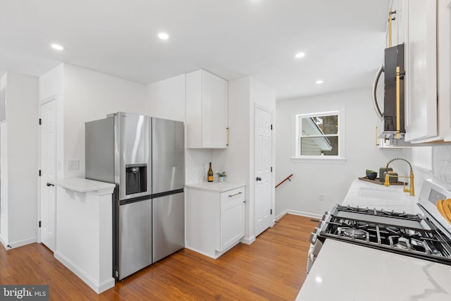 kitchen featuring stainless steel fridge with ice dispenser, light wood-type flooring, white cabinetry, and sink