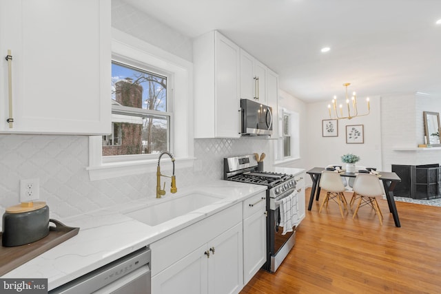 kitchen with decorative light fixtures, sink, white cabinetry, and stainless steel appliances