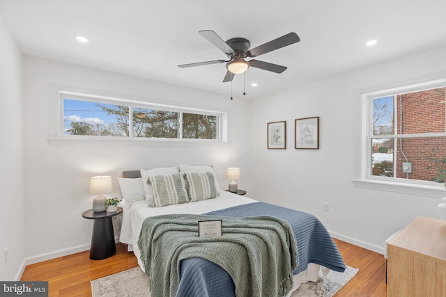 bedroom with hardwood / wood-style floors, ceiling fan, and multiple windows