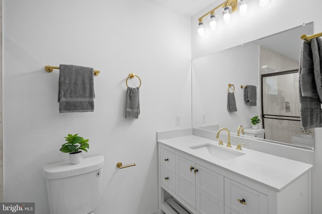 bathroom with vanity, a shower with shower door, and toilet