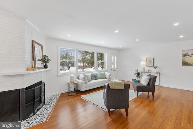 living room featuring a fireplace, light wood-type flooring, and ornamental molding