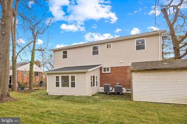 rear view of property featuring central air condition unit and a lawn