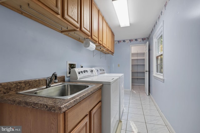 laundry room featuring washing machine and dryer, sink, light tile patterned flooring, and cabinets