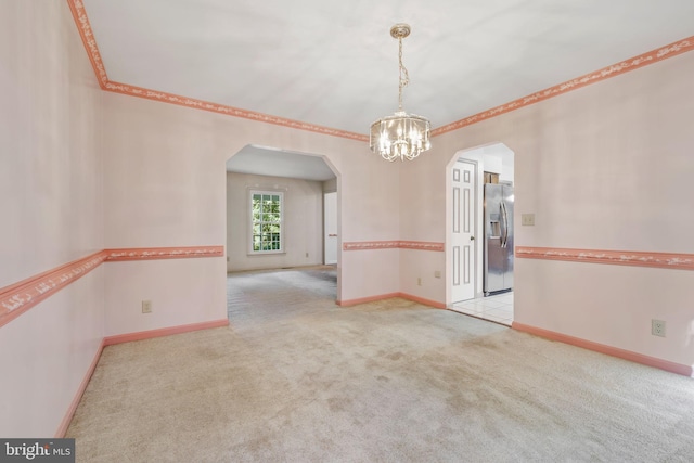 carpeted spare room with an inviting chandelier