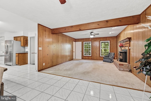 carpeted living room with a fireplace, ceiling fan, and wood walls