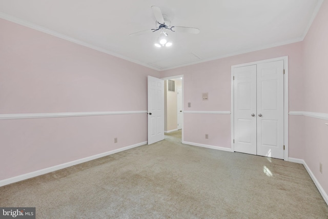 unfurnished bedroom featuring ceiling fan, a closet, light colored carpet, and ornamental molding