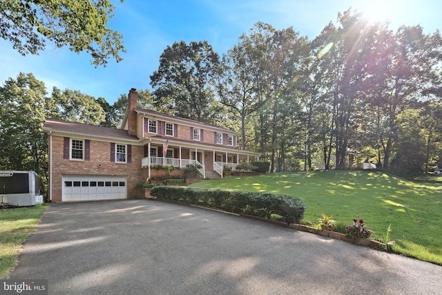 view of front of property featuring a porch, a garage, and a front yard