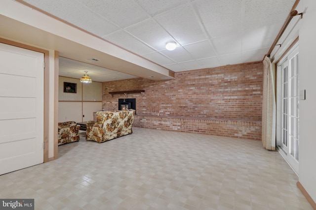 basement with a paneled ceiling and brick wall