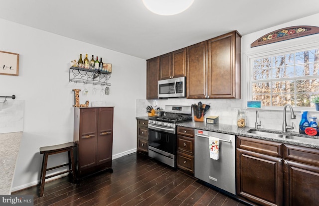 kitchen with sink, stainless steel appliances, dark wood-type flooring, backsplash, and dark stone counters