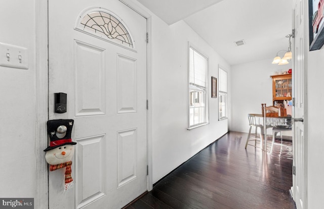 foyer entrance featuring a healthy amount of sunlight, dark hardwood / wood-style floors, and a notable chandelier