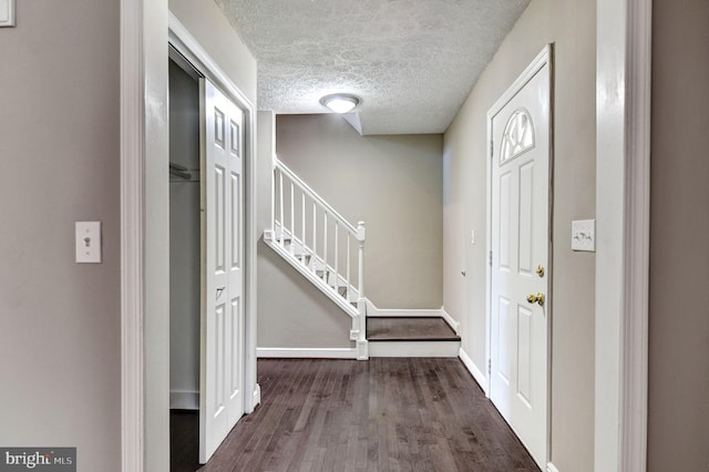 foyer entrance with a textured ceiling and dark wood-type flooring