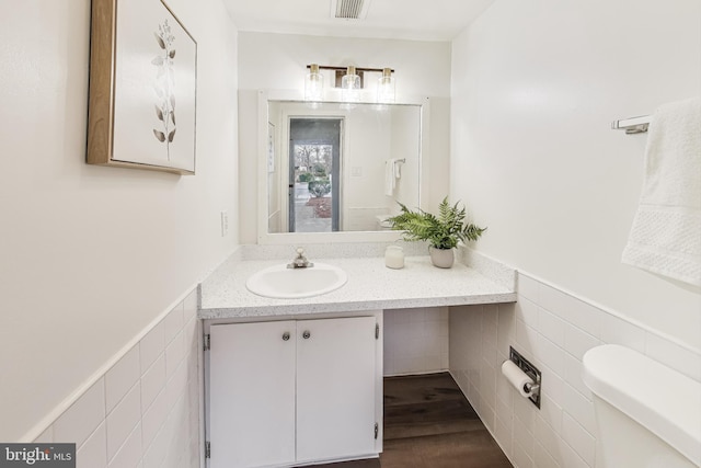 bathroom featuring vanity, tile walls, and toilet