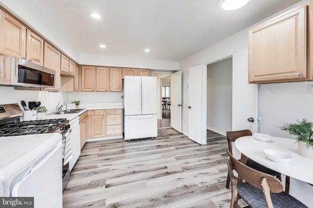 kitchen with appliances with stainless steel finishes, sink, light brown cabinetry, and light hardwood / wood-style flooring