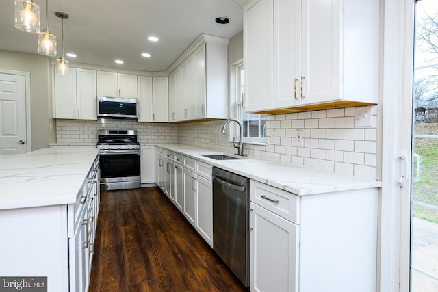 kitchen with pendant lighting, dark wood-type flooring, white cabinets, sink, and stainless steel appliances