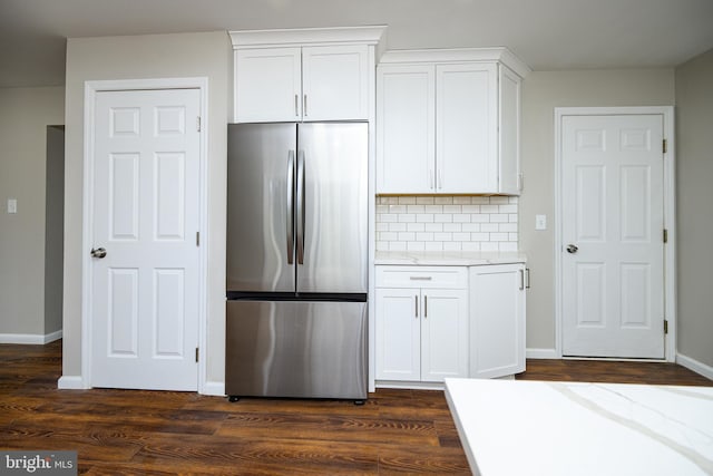 kitchen featuring stainless steel fridge, white cabinets, and light stone counters