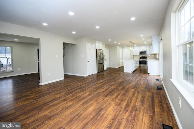 unfurnished living room featuring sink and dark hardwood / wood-style floors