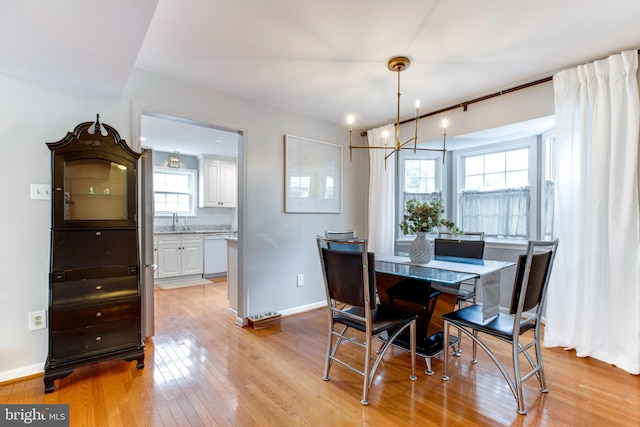 dining room with sink, light hardwood / wood-style floors, and an inviting chandelier