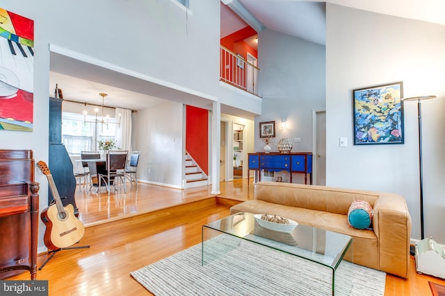 living room with a towering ceiling, a chandelier, and hardwood / wood-style flooring