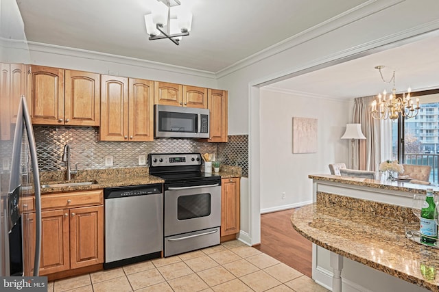 kitchen with sink, a notable chandelier, light tile patterned flooring, light stone counters, and stainless steel appliances