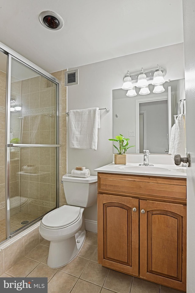 bathroom featuring tile patterned flooring, vanity, toilet, and walk in shower