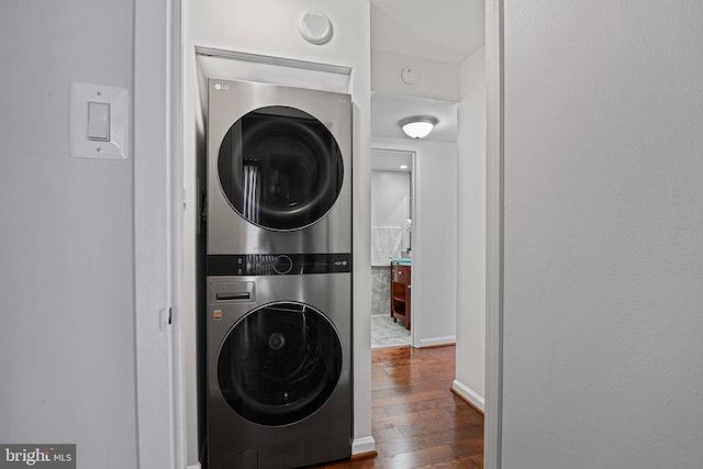 laundry area with dark wood-type flooring and stacked washer / drying machine