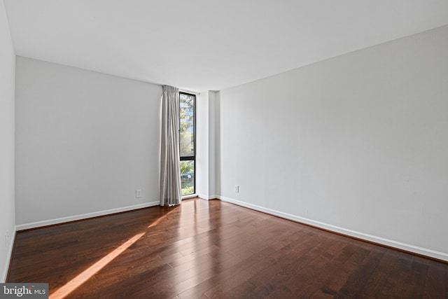 unfurnished room with dark hardwood / wood-style floors and floor to ceiling windows