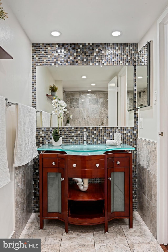 bathroom with vanity, decorative backsplash, and tile walls