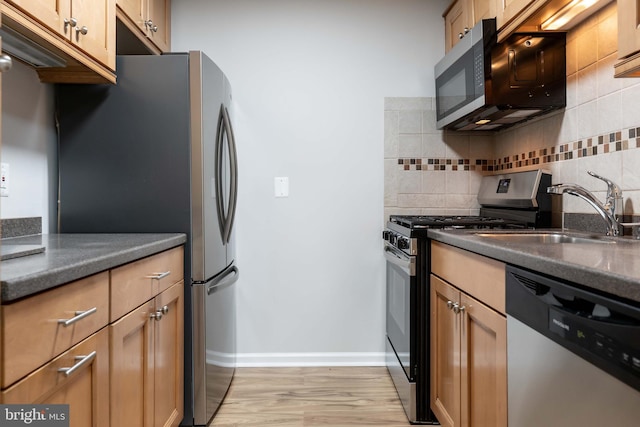 kitchen featuring tasteful backsplash, sink, light hardwood / wood-style floors, and appliances with stainless steel finishes