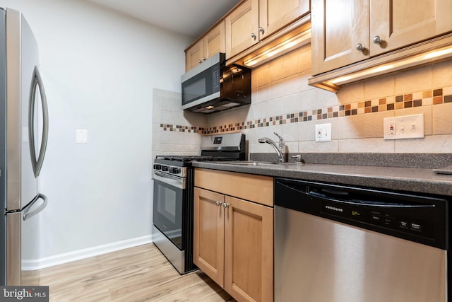 kitchen with backsplash, sink, stainless steel appliances, and light wood-type flooring