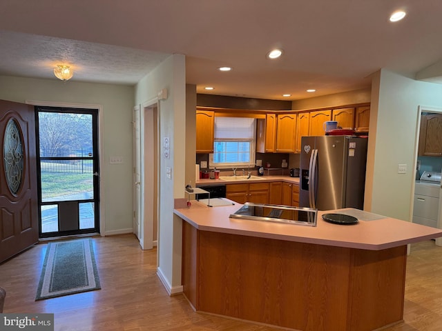 kitchen with sink, stainless steel refrigerator with ice dispenser, light hardwood / wood-style flooring, kitchen peninsula, and washer / clothes dryer