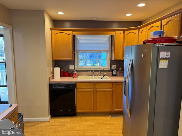 kitchen featuring dishwasher, stainless steel fridge, light hardwood / wood-style floors, and sink